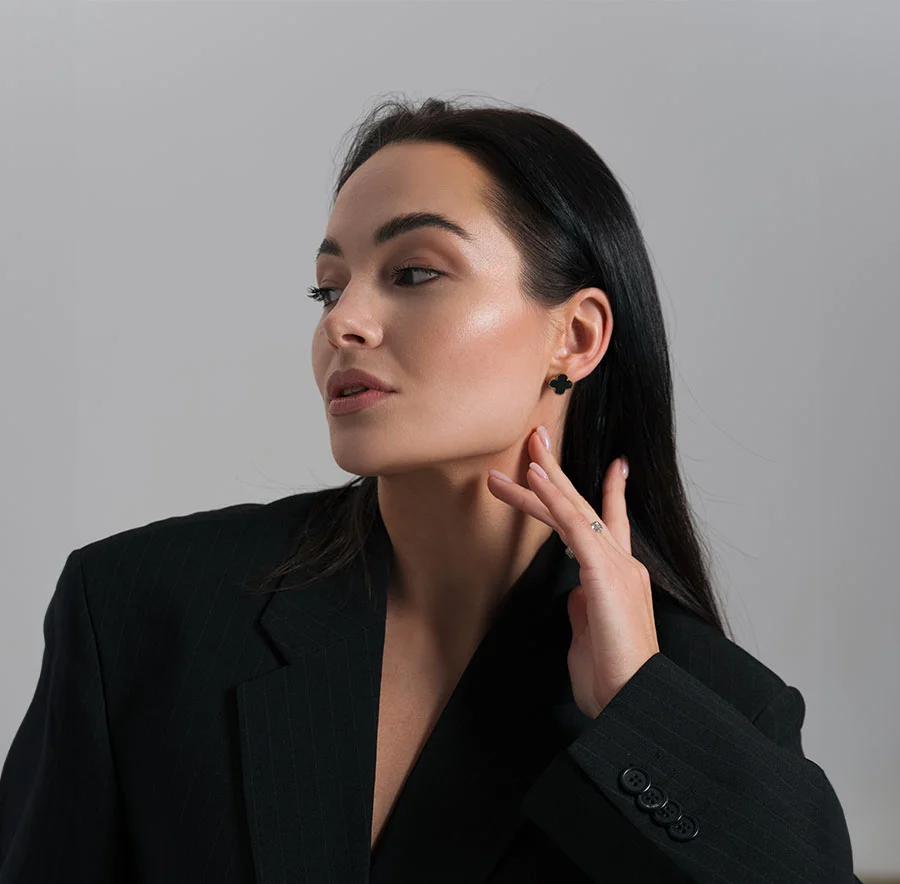 A dark haired woman in a black suit, looking to the side, with her hand lightly touching her neck - Neck Lift Procedure in Chicago, IL